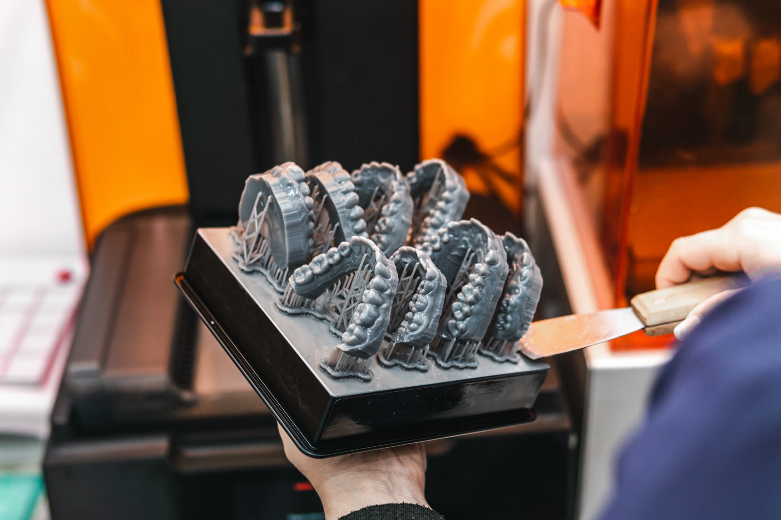 3D-printed jaw models coming out of the printer